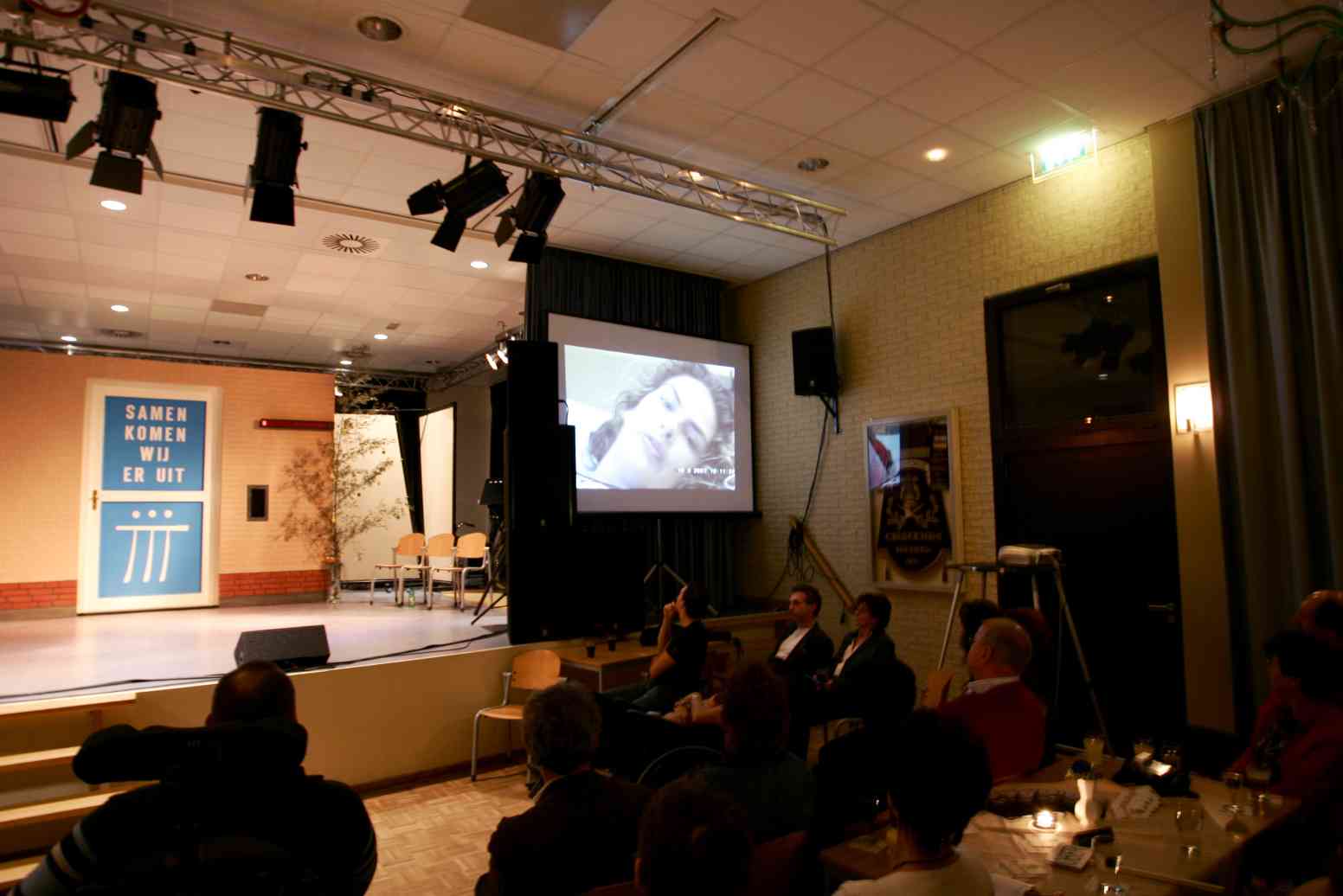 Veroni opent de avond door een filmpje. Ze kan er helaas niet bj zijn, maar via de webcam kan ze wel meekijken.